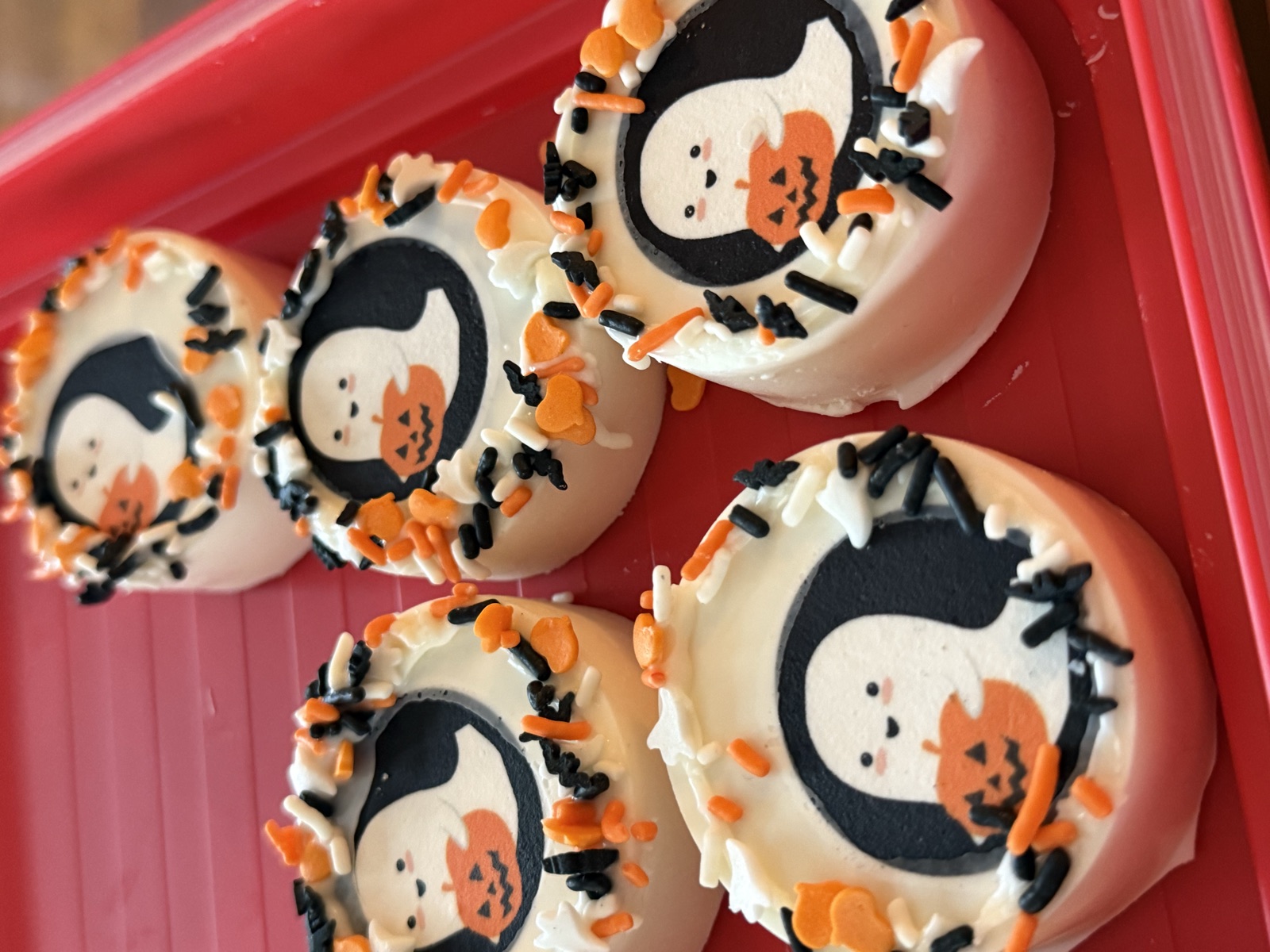 Dipped Oreos with ghost designs and Halloween sprinkles
