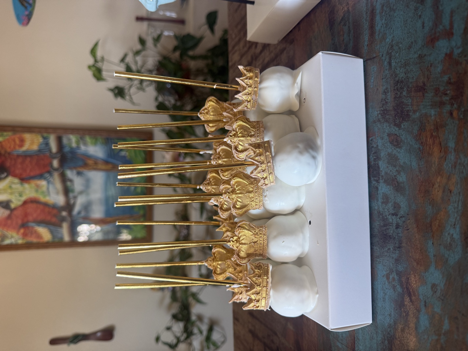 White cake pops topped with gold crowns on gold sticks